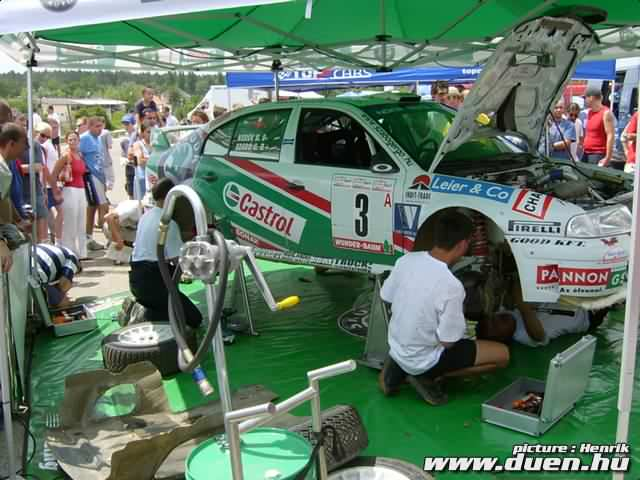 Mechanics working on a Castrol-liveried rally car under a service tent